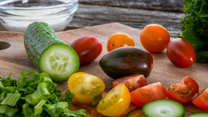 Tomatoes, lettuce and cucumber on cutting board