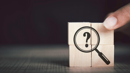  Hand hold magnifying glass and question mark sign icon in wooden cube. Problems and root cause...
