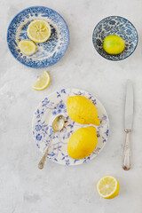 Vintage plates with yellow and green citrus next to old knife and spoon on white background