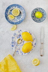 Vintage plates with yellow and green citrus next to old knife and spoon on white background and yellow napkin