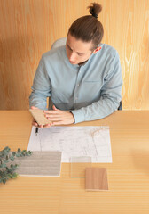 Vertical picture of man architect touching different materials for project