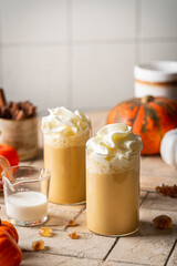 Autumn pumpkin spice latte with whipped cream and cinnamon on light background