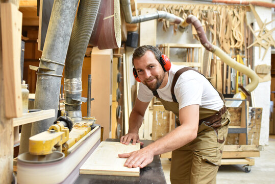 carpenter works in a joinery - workshop for woodworking and sawing