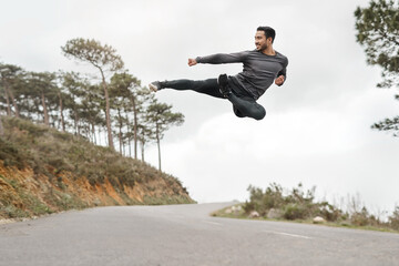 My body is built to overcome obstacles. Full length shot of a handsome young man doing a flying kick during his workout outdoors.