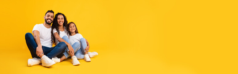 Happy Arabic Father, Mother And Daughter Embracing Sitting, Yellow Background