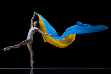 Young graceful classic ballerina dancing with cloth painted in blue and yellow colors of Ukraine...
