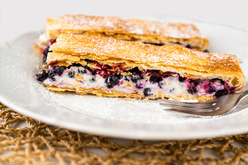 2  piece of cake from puff pastry with blueberry and cream on plate.