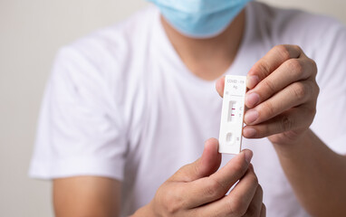man holding Rapid Antigen Test kit (ATK) with Positive result during swab COVID-19 testing,...