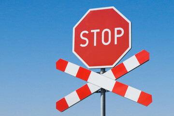 Stop sign background. Long railway landscape. Road sign suggesting caution. Watch out for a train. Rail crossing danger background. Object isolated on blue sky.