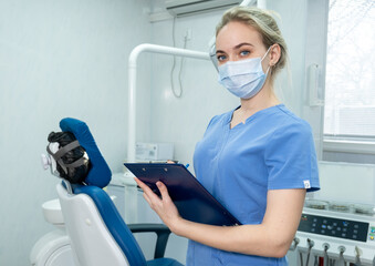 Dentist assistant or nurse in protective face mask in dentistry room