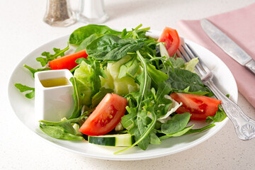 Fresh spring garden salad with arugula, tomato and dressing in a light bright environment