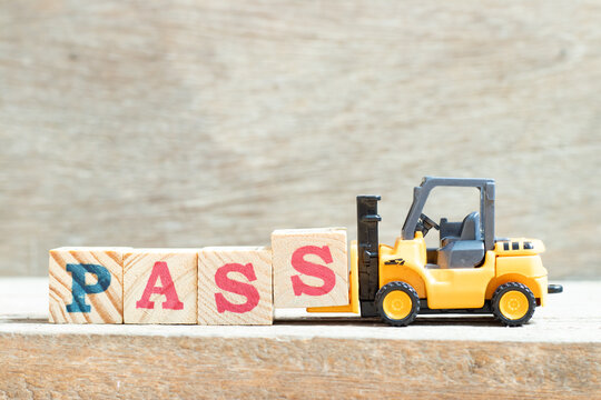 Toy forklift hold letter block s to complete word pass on wood background