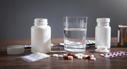 Medical pills and glass of water on the table.