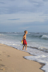 A child on the beach plays in the waves of the ocean. Boy on the ocean, happy childhood. tropical life.