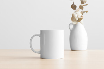 White mug mockup with an eucalyptus decoration on the wooden table.