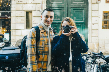 Cute couple taking a photo in a dirty old mirror on the street, traveling together.
