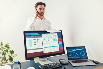 Man entrepreneur having business  conversation on mobile phone. Businessman holding documents and smartphone working with data on charts and graphs in office