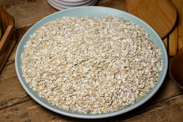 Dry oatmeal in a plate on a wooden background. Healthy and tasty food. Food for weight loss