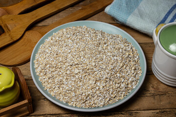 Dry oatmeal in a plate on a wooden background. Healthy and tasty food. Food for weight loss