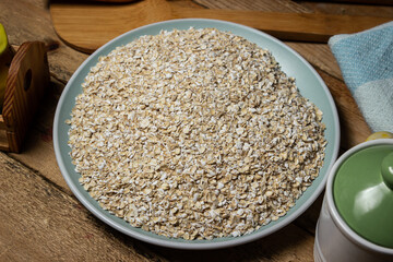 Dry oatmeal in a plate on a wooden background. Healthy and tasty food. Food for weight loss