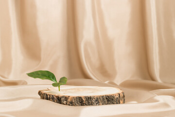 Empty wooden podium with bark and green leaf on satin beige textile, natural tree display for...