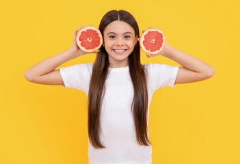 cheerful child with grapefruit and book on yellow background, diet