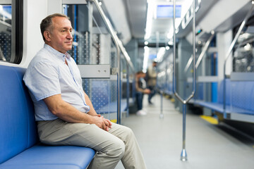 Positive elderly man sitting in an empty subway carriage while train is moving
