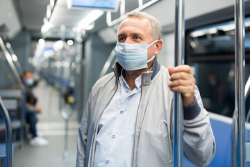 Fototapeta na wymiar Middle aged man in face mask in subway car