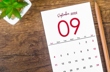 September 2022 calendar and wooden pencil on wooden background.