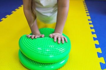 a little girl walks with her feet on a studded ball in the children's center as if on a track