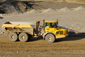 Yellow dump truck working in gravel pit