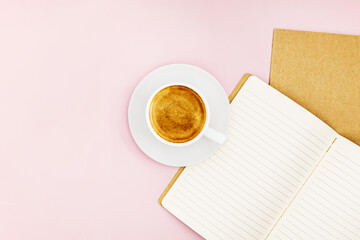 Top view mock-up close-up of two notebooks for writing and a white porcelain cup with coffee on a pink background. Selective focus.