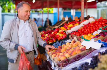 Middle aged man buying peaches