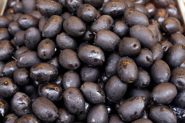 Black olives close up on market, food background