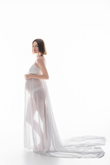 Fototapeta premium Pregnant woman in cloth and panties looking at camera on white background