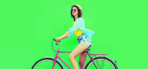 Summer colorful image of happy smiling young woman with bicycle on vivid green background