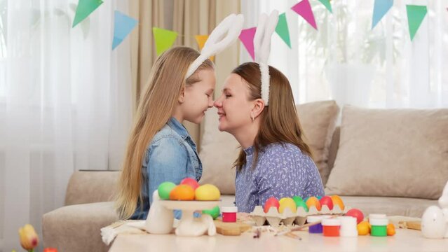 mom and daughter with rabbit ears celebrate Easter and cuddle and kiss 