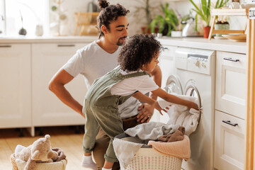Son helping dad to load washing machine