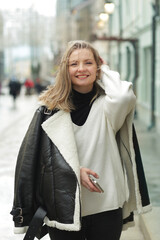 Fototapeta premium young blond slavic woman with cell phone in black leather jacket close up street portrait 