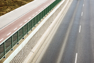 Obraz premium Bike trail along a highway. Top view road background. Urban transportation landscape. Pavement, sidewalk and cycling path next to each other. Car road nearby.