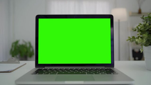 Green screen desktop set on table. Empty living room with modern chroma key green screen mock up computer set up for online videocall meeting. Pc with isolated display in home office