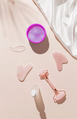 Creative composition made of cosmetic facial kit for home skin care and spa. Collagen eye patches, face roller and gua sha massagers, bottle of essential oils or serum. Top view. Flat lay