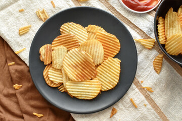 Crisps or Potato chips on a black plate. Flat lay top view food photo. Food from above concept.	
