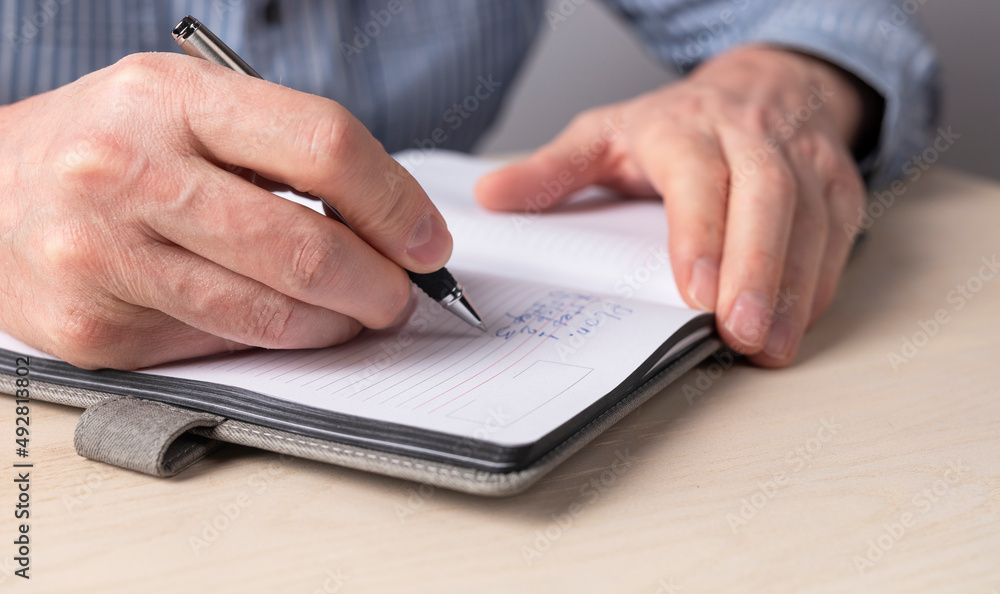 Poster Man hands closeup taking notes in planner. Man sitting at table in office or at home, working or studying and writing agenda, thoughts, important information in organizer. High quality photo