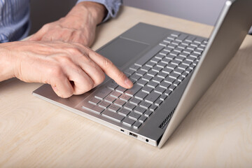 Man hands closeup using laptop and pressing enter key. Typing message, information search, making project, using computer for work and education concept. High quality photo