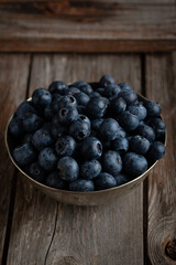 Bowl of fresh blueberries on rustic wooden table with copy space.