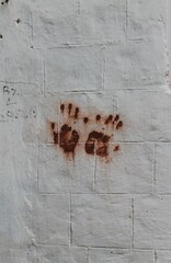 Two red painted human hand palms on a white stone wall