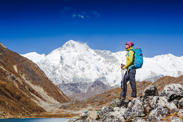 Naklejka na ściany i meble Woman Traveler with Backpack hiking in Mountains with beautiful summer Himalayas landscape on background. Everest Base Camp trek. Cho oyu mountain on the background