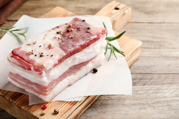 Tasty salt pork with rosemary and spices on wooden table, closeup. Space for text