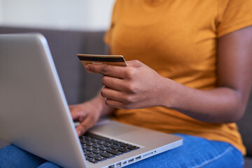 A close up of a young woman holding a credit card and shopping online